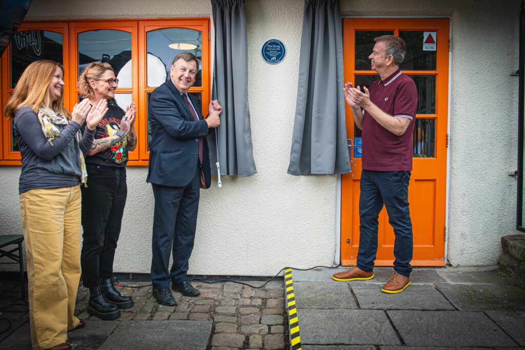 The unveiling of the Music Venue Properties Plaque on the wall at The Snug Coffee House in Atherton