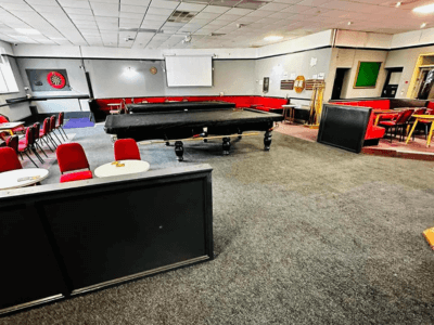 a large room with a pool table and red chairs